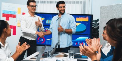 Analyst team leader shake hand with his colleague after successful data analysis meeting using FIntech software power with business intelligence or BI dashboard. Prudent